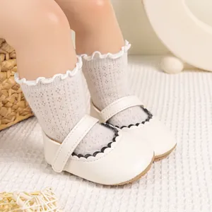 Detailopname van witte Mary Jane babyschoentjes met zwarte geschulpte rand en kanten sokken