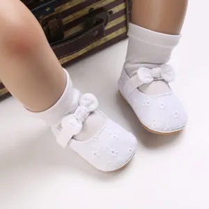 Primer plano de zapatos de princesa para bebé blancos con bordado y un lazo