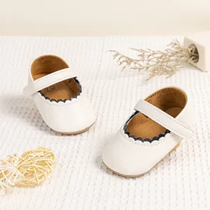 Detailopname van witte baby Mary Jane schoentjes met zwarte geschulpte randafwerking.