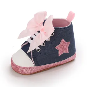 Detalle de zapatillas vaqueras para bebé niña con estrella de purpurina y lazo grande