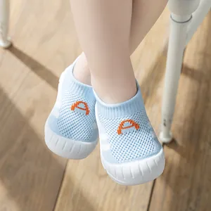 Detailed view of light blue knitted baby walking shoes with soft soles on wooden floor