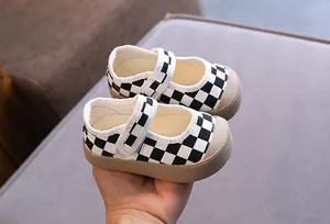 Gros plan de chaussures de marche pour bébé à semelle souple avec motif à carreaux