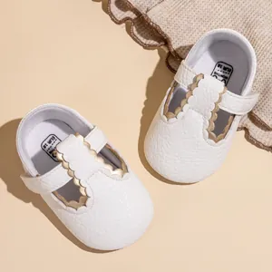 Bovenaanzicht van elegante witte baby Mary Jane-schoenen met decoratieve gouden schulprand