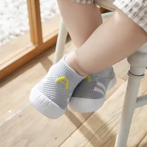 Detailed view of baby's feet in breathable grey knit soft-sole walking shoes for indoor use