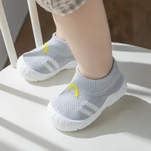 Close-up of breathable grey fly-knit baby walking shoes with soft white rubber soles