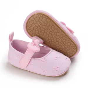 Detalle de zapatos de princesa rosa para bebé con bordado de flores y lazo
