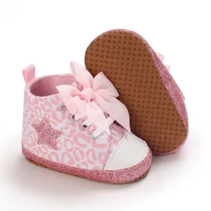 Primer plano de zapatos de bebé rosa con estampado de leopardo, lazo y estrella