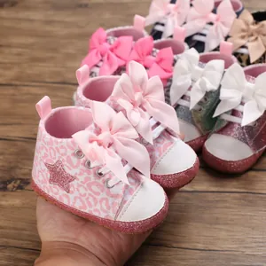 Detalle de zapatos de bebé con estampado de leopardo rosa, estrellas y lazos