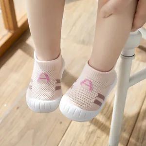 Close-up of pink fly-woven baby walking shoes with soft soles on a wooden floor