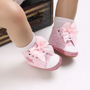 Detalle de zapatos para bebé niña con estampado de leopardo rosa, lazos y suela brillante