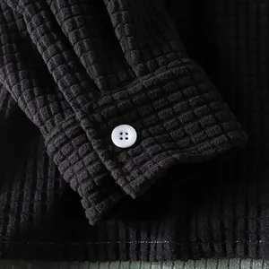 Close-up view of a black waffle textured shirt cuff featuring a white button detail