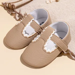 Detailopname van beige baby Mary Jane schoentjes met witte schulprand en leertextuur.