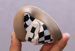 Vue détaillée de la semelle souple et flexible d'une chaussure bébé à damier noir et blanc