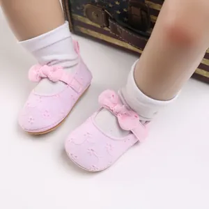 Detalle de zapatos de princesa rosa para bebé con bordado floral y lazo suave.