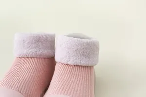 Nahaufnahme von rosa Babysocken-Schuhen mit warmem Fleecekranz und weichem Strick.