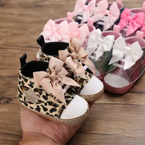 Primer plano de zapatos para bebé con estampado de leopardo y un gran lazo rosa.