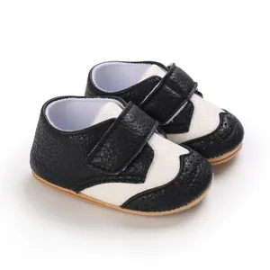 Detail of black and white baby toddler shoes with non-slip sole and hook-and-loop strap.