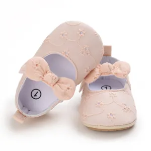 Primer plano de zapatos de princesa rosa para bebé con bordado floral y un lazo