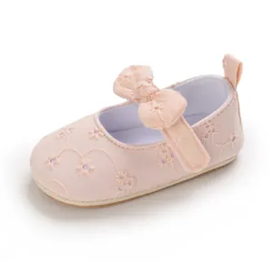 Primer plano de zapato princesa rosa para bebé con bordado floral y detalle de lazo