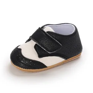 Detailed macro view of black and white baby walking shoes with anti-slip gum sole.