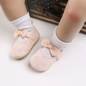 Vista detallada de los zapatos rosa de princesa para bebé con lazo y bordados.