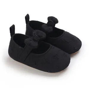 Detalle de zapatos de princesa para bebé negros con suela blanda, lazo y bordado