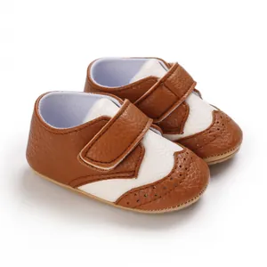 Detailed view of brown and white baby walking shoes with elegant brogue perforation details