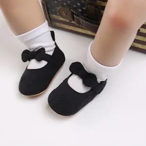 Primer plano de zapatos de princesa para bebé en negro con lazo y suela blanda