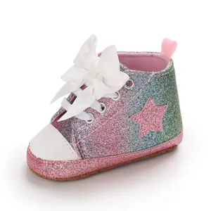 Detalle de zapatos para bebé niña con purpurina, lazo blanco grande y parche de estrella rosa.