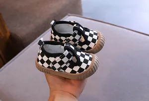 Close-up view of black and white checkerboard baby walking shoes with soft rubber sole