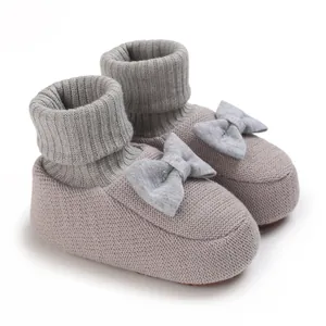 Vue détaillée de ces chaussons tricotés pour bébé ornés d'un joli nœud décoratif