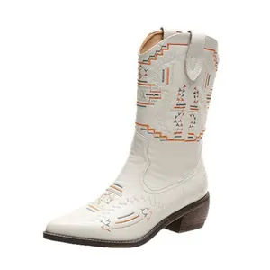 Close-up detail of white embroidered mid-calf cowboy boots with western style patterns