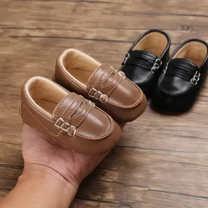 Primo piano di mocassini per bambini in pelle marrone e nera con suola morbida su legno.