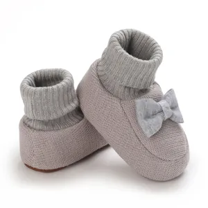 Vue détaillée de chaussons tricotés pour bébé avec un nœud et des bords côtelés
