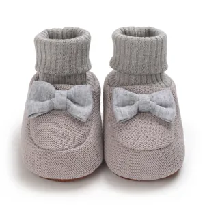 Gros plan de chaussons en tricot gris doux pour bébé avec nœud décoratif élégant