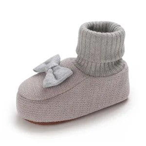 Détail de chaussures de marche tricotées pour bébé avec col en maille côtelée et nœud décoratif