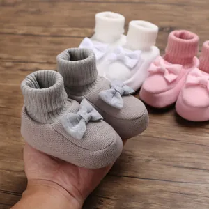 Détail de chaussons en tricot doux pour bébé avec un joli nœud et bords côtelés.