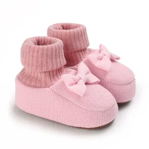 Détail de chaussons en tricot rose pour bébé avec semelles souples et nœuds décoratifs
