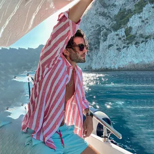 Stylishly dressed man wearing a pink striped breathable long-sleeved shirt on a boat