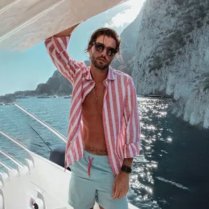 Model wearing a pink and white striped breathable beach shirt on a sunny yacht deck