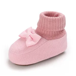 Vue détaillée de chaussons en tricot rose avec nœud et revers côtelés doux.