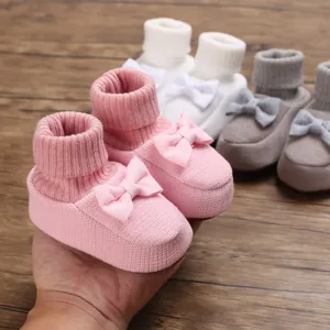 Gros plan détaillé de chaussures pour bébé en tricot rose avec un joli nœud et bord-côte.