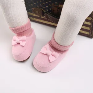 Gros plan sur des chaussons en tricot rose avec nœuds mignons portés par un nourrisson