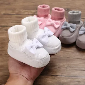 Gros plan de chaussures de bébé en tricot souple avec nœuds décoratifs pour tout-petits
