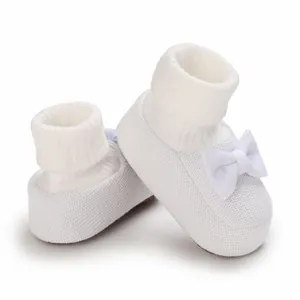 Détail de chaussures de bébé en tricot blanc avec un joli nœud et une semelle souple