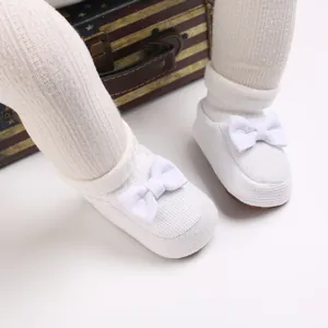 Gros plan de chaussures en coton tricoté blanc pour bébés avec semelle souple et nœud