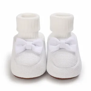 Détail de chaussons bébé tricotés blancs avec semelle souple et nœud pour nouveau-né.