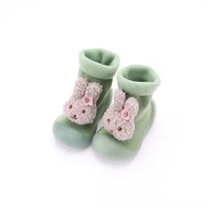 Primer plano de zapatos calcetín de punto verde para bebé con conejo de peluche 3D