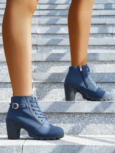 Detailansicht von schicken marineblauen Schnürstiefeletten mit hohem Absatz auf Steintreppen.