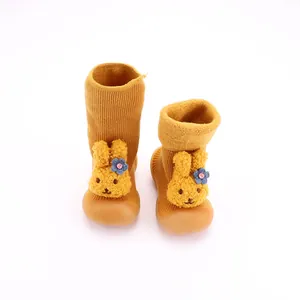 Primer plano de zapatos tipo calcetín para bebé con adorno de conejito de peluche.